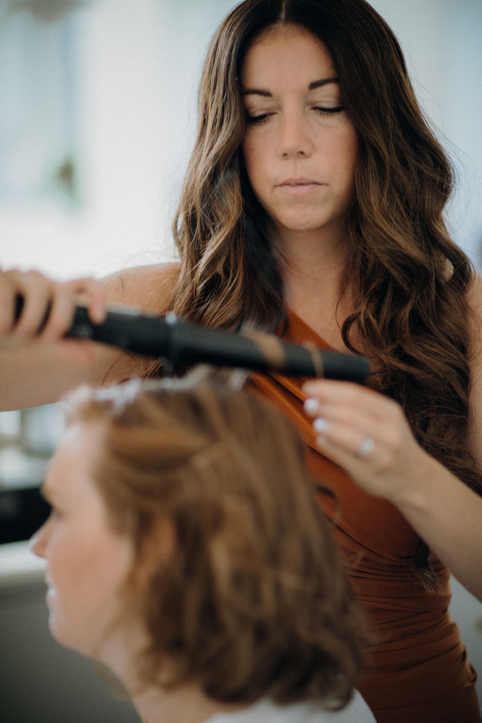 A hairstylist meticulously curls a client's hair using a curling iron, capturing the art of hairstyling.