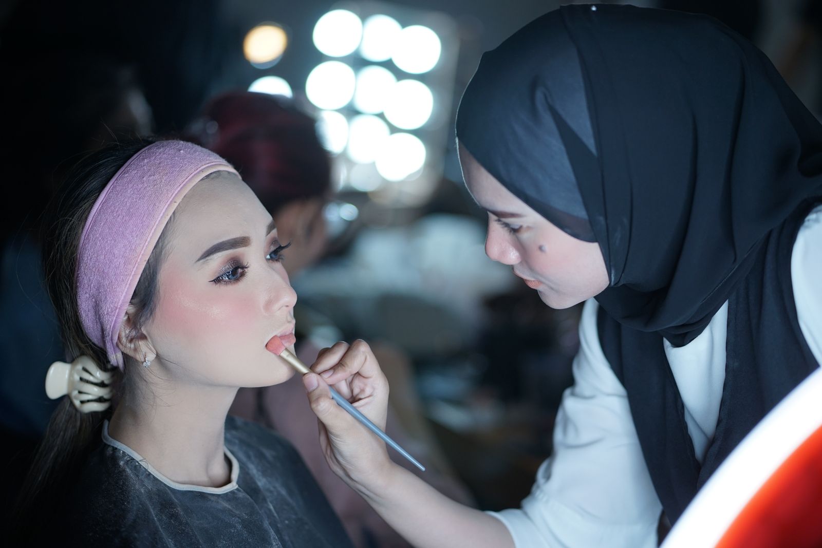 A makeup artist applying lipstick in a studio