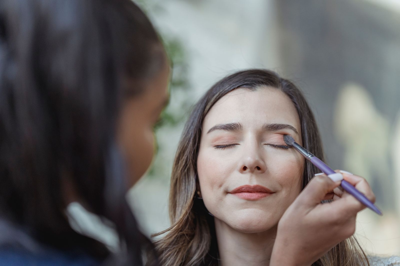 A makeup artist applying eyeshadow to a bride
