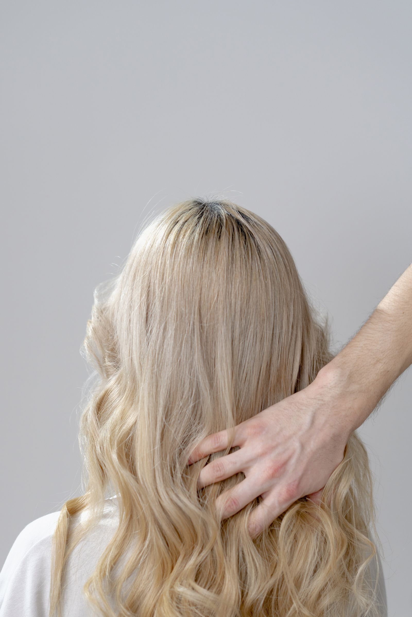 A woman with blonde curls styled gently in a hair salon setting.