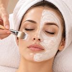 A therapist brushing a cream mask onto a client's cheek
